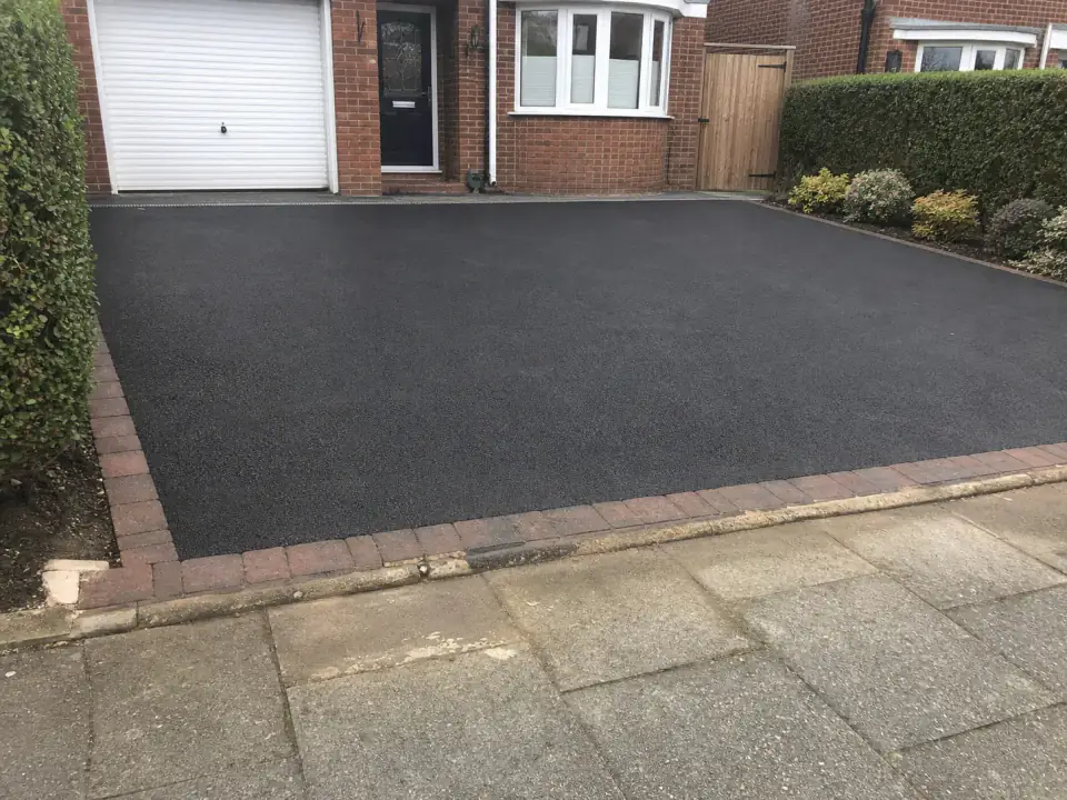 Dark tarmac driveway with a block-paved border at a modest UK home