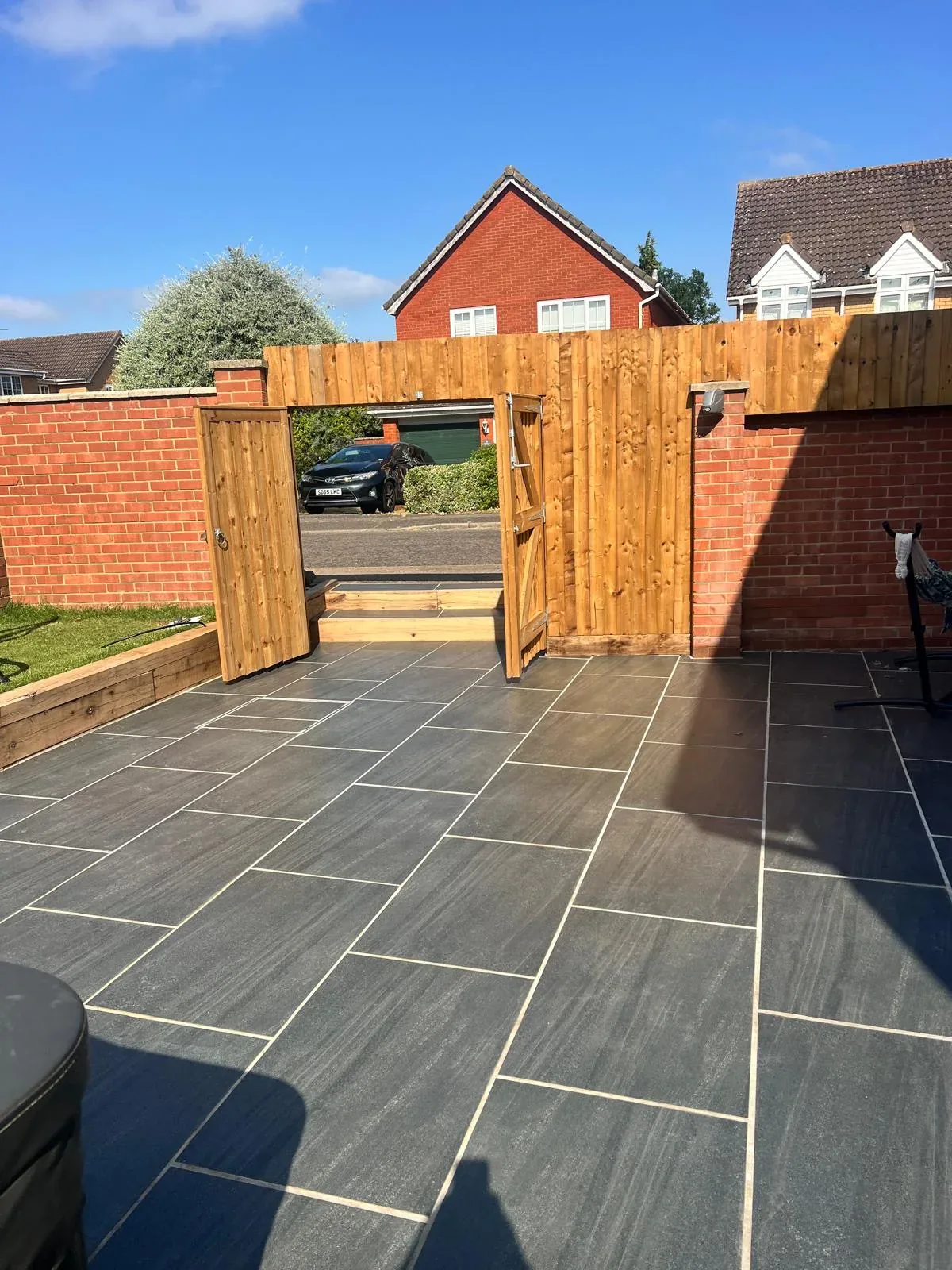 Completed porcelain patio leading through new timber double gates