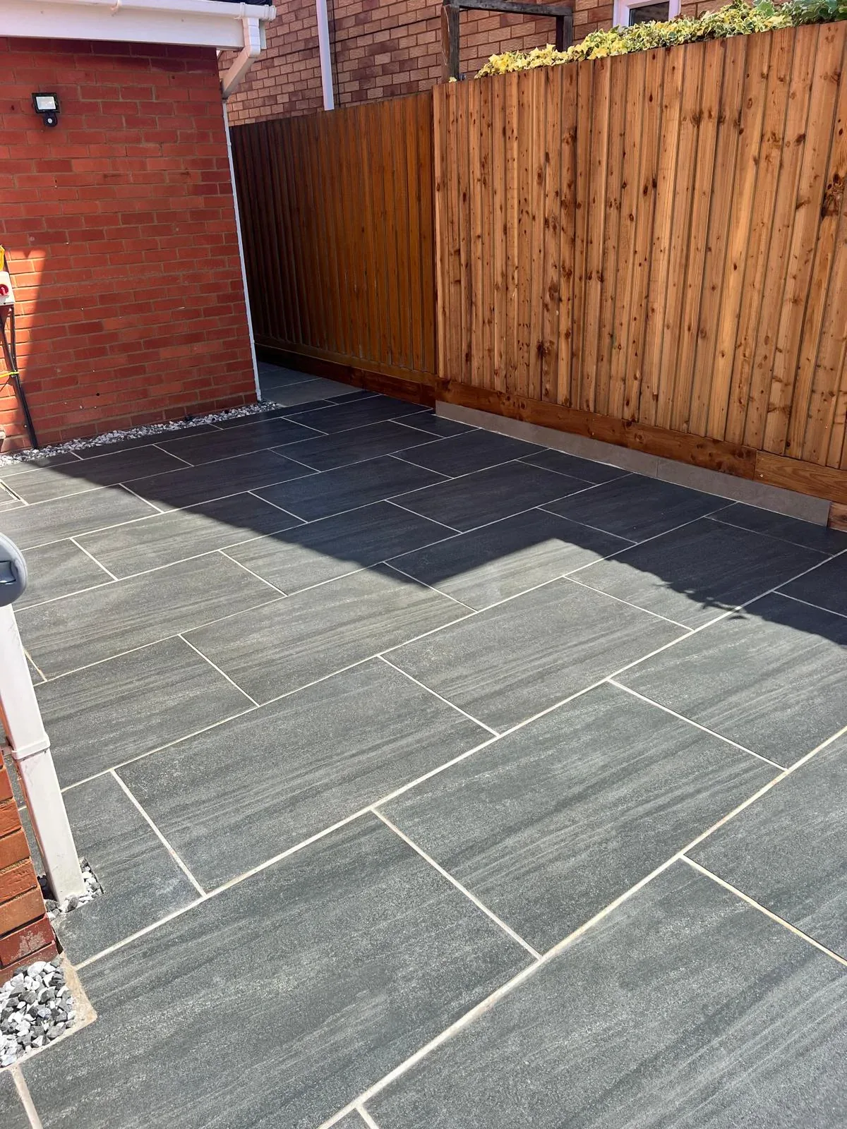 Completed dark porcelain patio meeting a new timber garden boundary