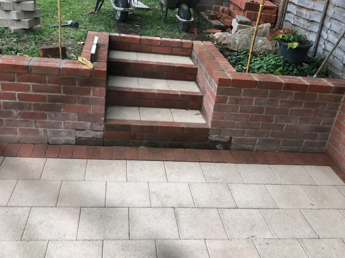 Brick garden steps and retaining walls beside a paved patio