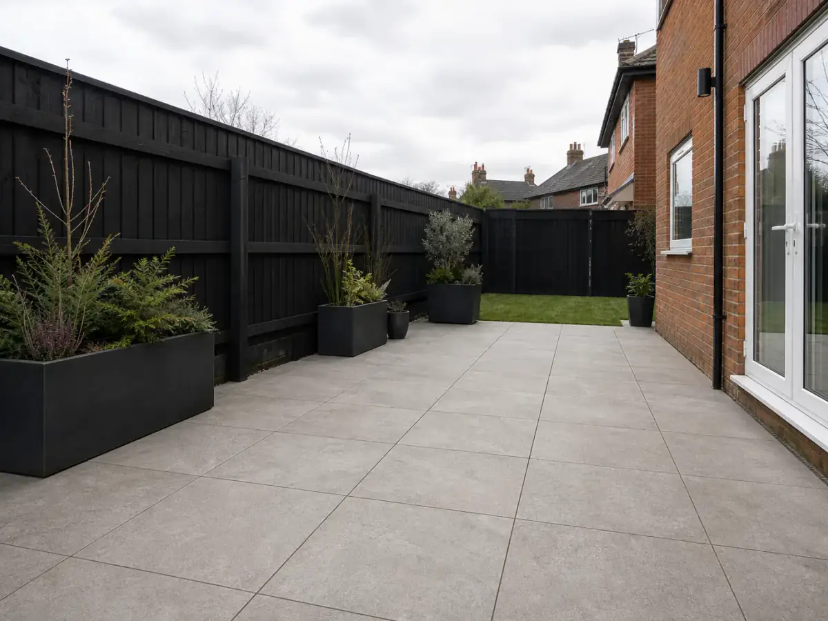 Warm-grey paved patio beside a red-brick home with a practical garden layout